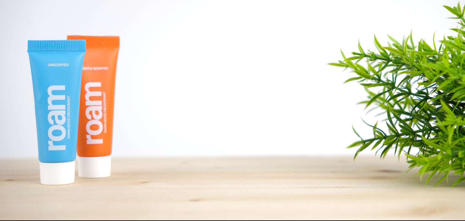 Two 'roam' branded tubes on a wooden surface with a plant in the background
