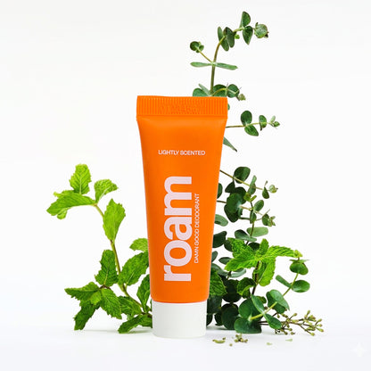 Orange tube of 'roam' deodorant with green leaves on a white background